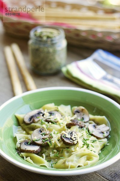 Homemade kale and walnut pesto ravioli with mushrooms and vegan cheese and chives