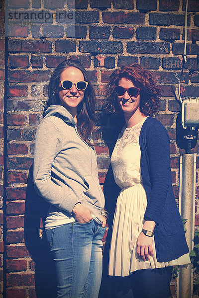 Zwei junge lächelnde Frauen mit Sonnenbrille