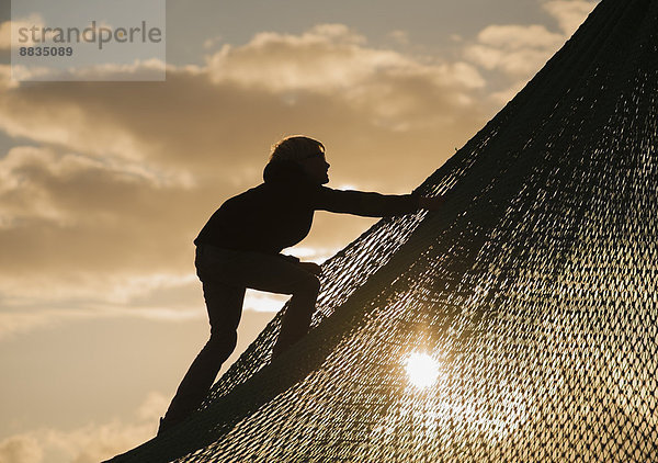 Denmark  Jutland  Vejers  climbing boy at sunset
