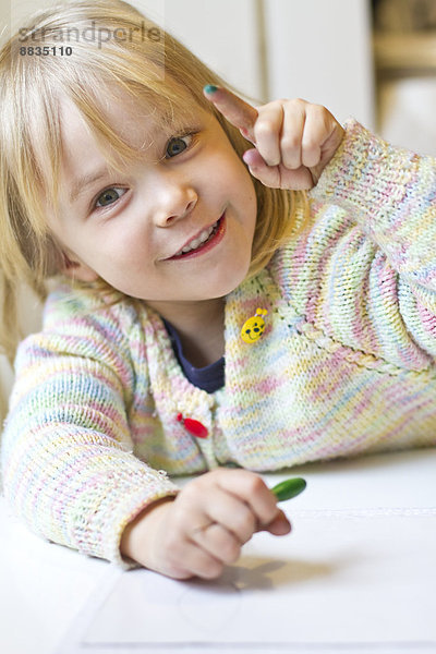 Porträt eines lächelnden kleinen Mädchens mit buntem Finger