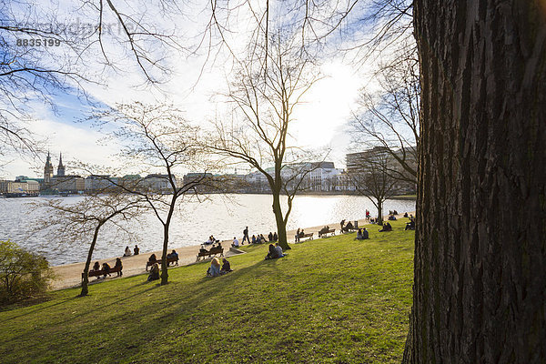 Deutschland  Hamburg  Binnenalster im Frühjahr  Menschen auf der Wiese am Seeufer