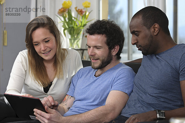 Drei Freunde mit Tablet-Computer zu Hause
