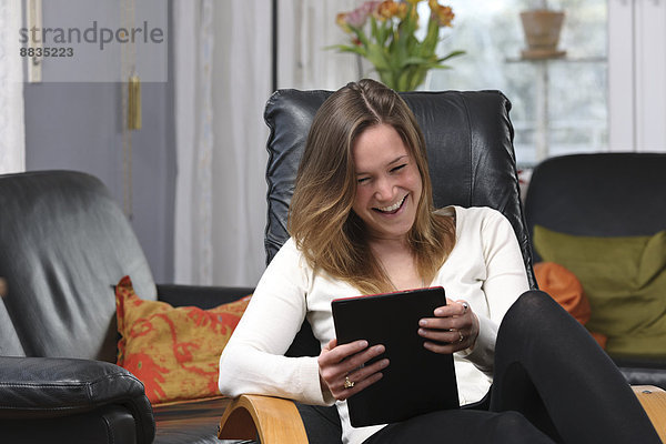 Junge Frau mit Spaß am Tablet-Computer zu Hause