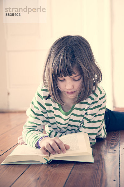 Porträt des kleinen Mädchens beim Lesen zu Hause