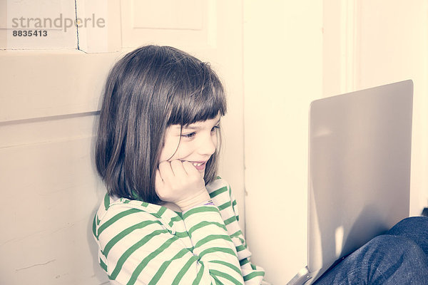 Porträt des kleinen Mädchens mit Laptop zu Hause