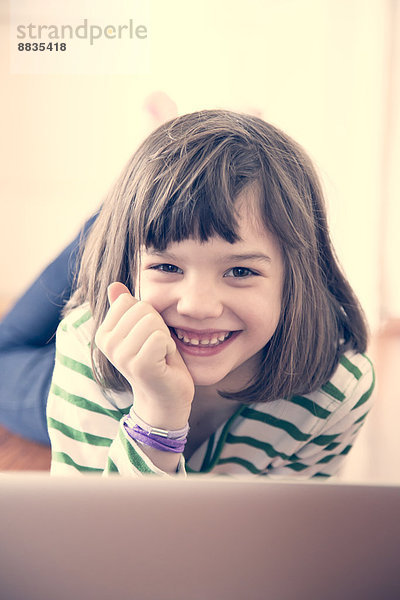 Porträt des lächelnden Mädchens mit Laptop zu Hause