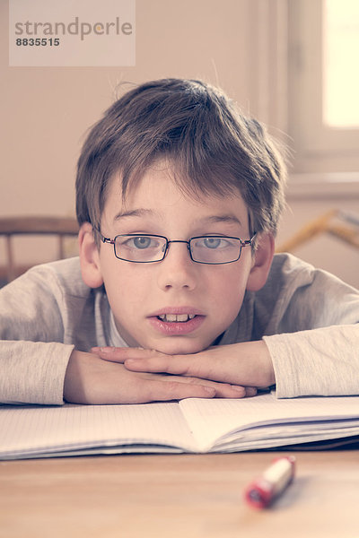 Porträt des kleinen Jungen bei den Hausaufgaben