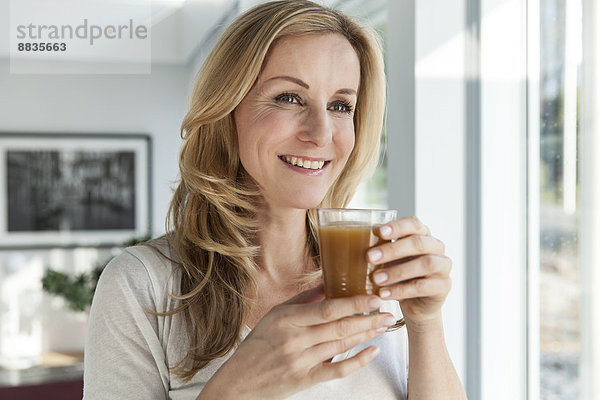 Porträt einer glücklichen Frau mit Getränk in ihrem hellen  modernen Zuhause
