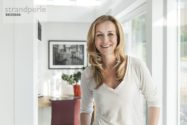 Porträt einer glücklichen Frau  die in ihrem hellen  modernen Haus steht.