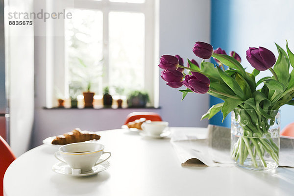 Breakfast table with tulips  croissants and cups of coffee