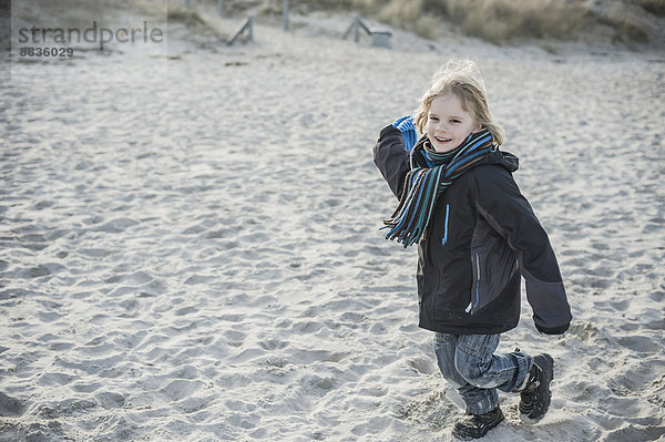 Deutschland  Mecklenburg-Vorpommern  Rügen  lächelnder kleiner Junge  der im Winter am Strand rennt.