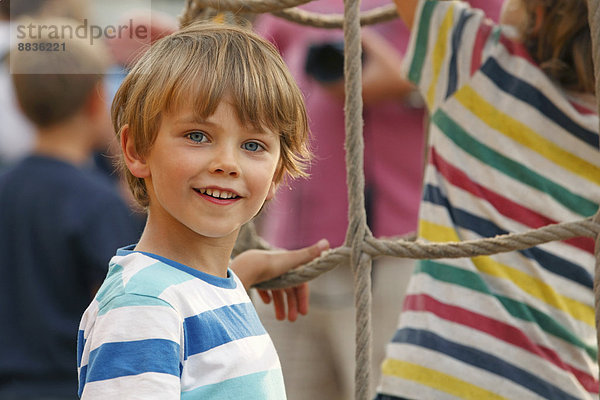 Porträt des lächelnden kleinen Jungen vor dem Kletternetz
