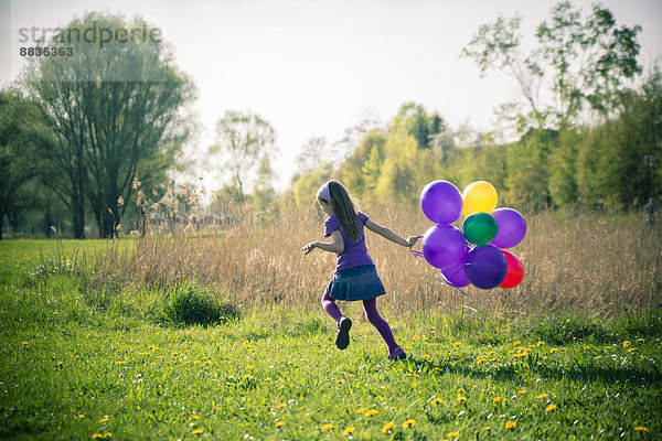 Kleines Mädchen mit Luftballons auf der Wiese