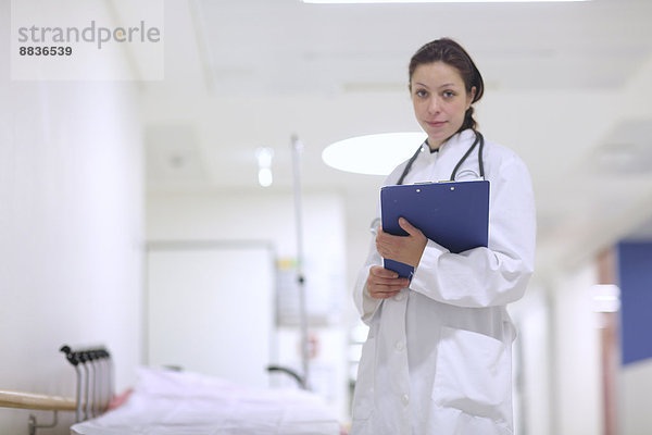 Porträt einer jungen Ärztin im Krankenhaus mit Klemmbrett