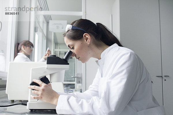 Porträt einer jungen Studentin am Mikroskop im Labor