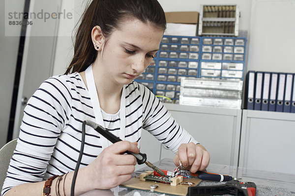 Junge Frau bei der Arbeit am optischen Sensor in einer Elektronikwerkstatt