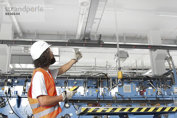 Arbeiter mit Schutzhelm in einer Fabrikhalle