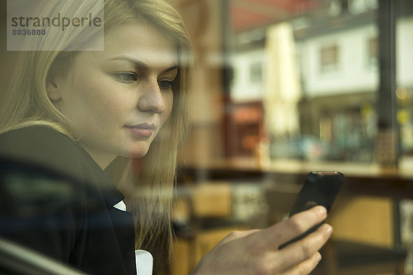 Young businesswoman in coffee shop  checking mobile phone