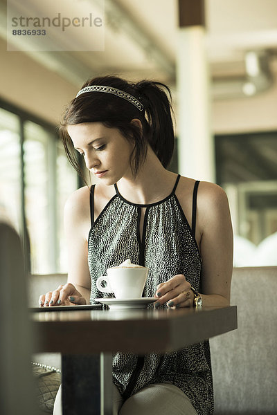 Porträt einer jungen Frau mit Tablet-Computer im Cafe