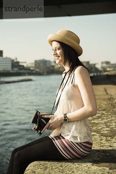 Porträt einer jungen Frau mit alter Kamera und Sommerhut