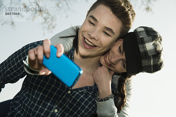 Porträt eines jungen Paares  das sich mit dem Smartphone fotografiert.