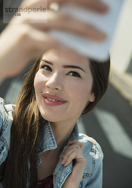 Brünette junge Frau mit einem Selfie im Freien