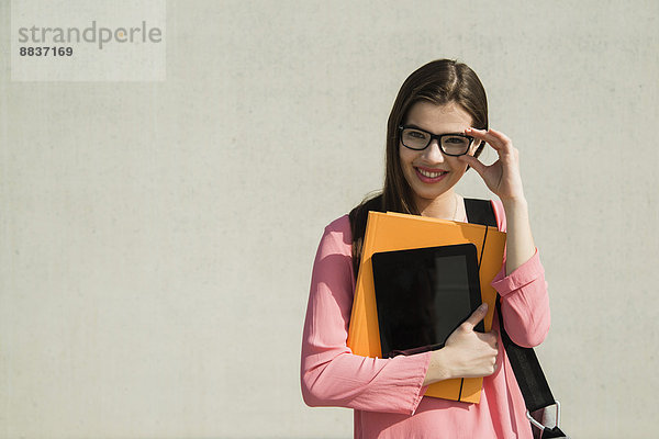 Brunette young woman with bag  folder and digital tablet outdoors
