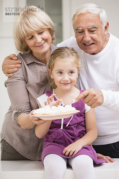 Portrait eines älteren Ehepaares mit Enkelin in der Küche