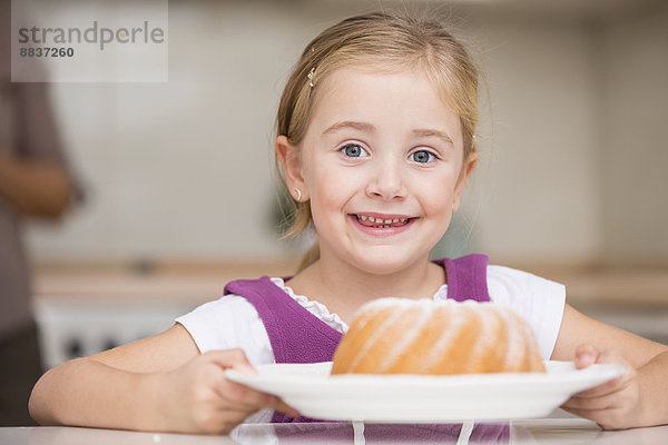 Porträt des lächelnden Mädchens mit Teller mit Ringkuchen