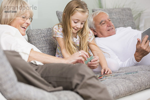 Seniorin und Enkelin beim gemeinsamen Spielen auf dem Sofa im Wohnzimmer