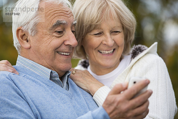Porträt eines lächelnden älteren Paares  das sich auf dem Smartphone selbst porträtiert.