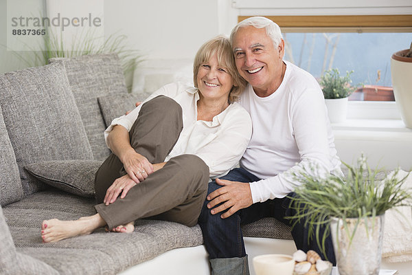 Happy Senior Paar Seite an Seite auf dem Sofa im Wohnzimmer