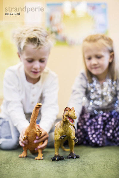 Kinder beim Spielen mit Spielzeugdinosauriern im Kindergarten