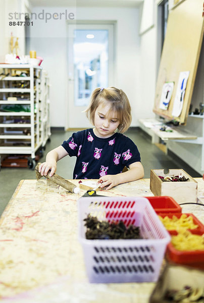 Mädchen machen Kunstprodukt am Tisch im Kindergarten