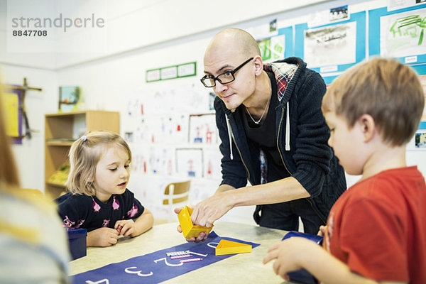 Lehrer  der die Schüler in der Kunstklasse des Kindergartens unterstützt.