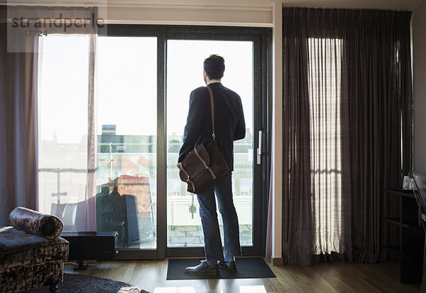 Rückansicht des Geschäftsmannes mit Blick durchs Fenster im Hotelzimmer