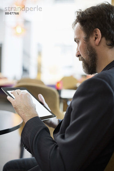 Seitenansicht des Geschäftsmannes mit digitalem Tablett im Hotelrestaurant