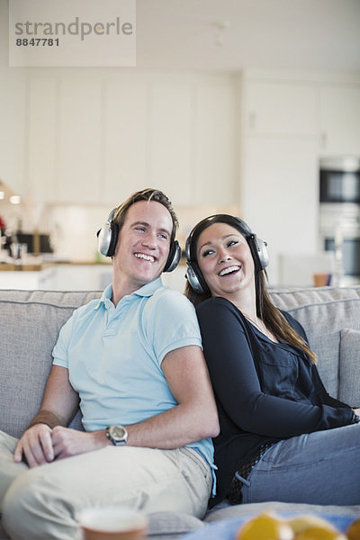 Glückliches Paar beim Musikhören auf dem Sofa zu Hause