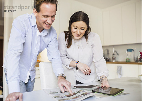 Glückliches Paar mit digitalem Tablett beim Betrachten des Katalogs in der Küche