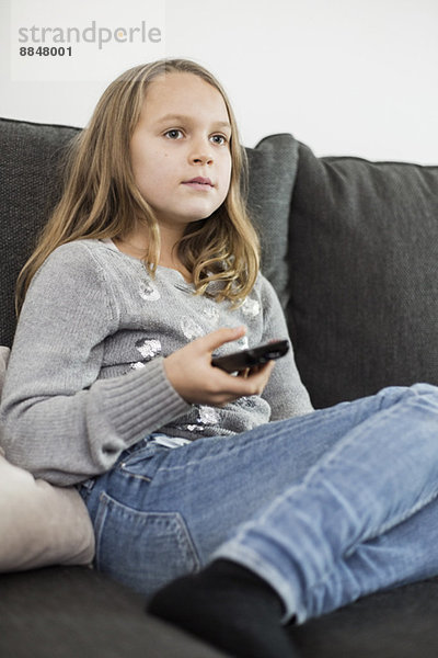 Mädchen beim Fernsehen auf dem Sofa zu Hause