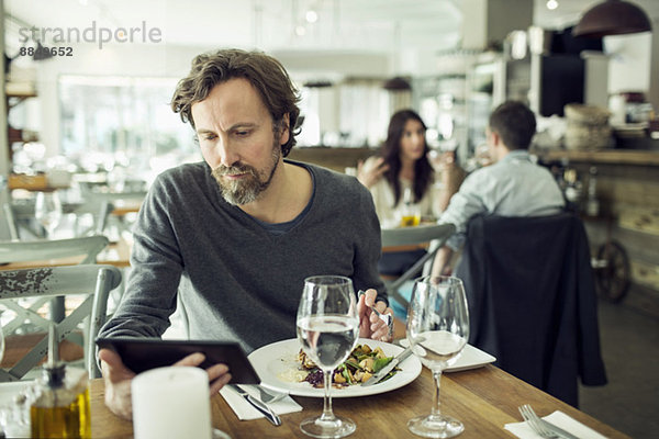 Erwachsener Mann mit digitalem Tablett im Restaurant