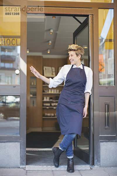 Volle Länge der glücklichen Besitzerin beim Stehen am Café-Eingang