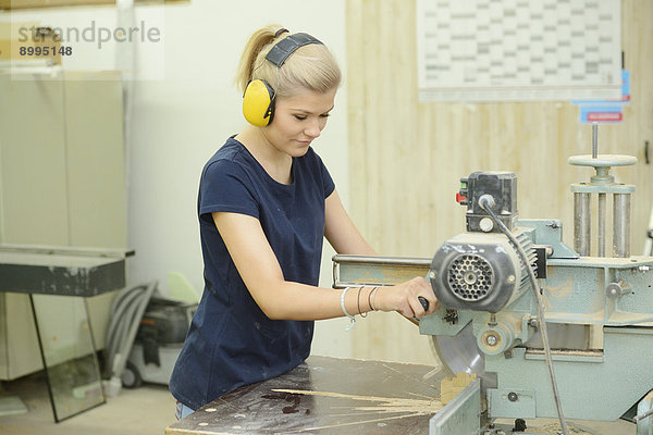 Junge Frau arbeitet in einer Schreinerei an einer Kreissäge