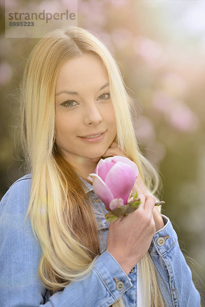 Junge blonde Frau in einem Park im Frühling