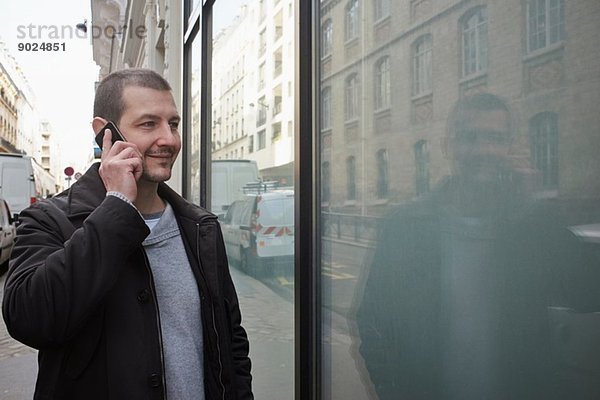 Mittlerer Erwachsener Mann beim Schaufensterbummel auf dem Smartphone