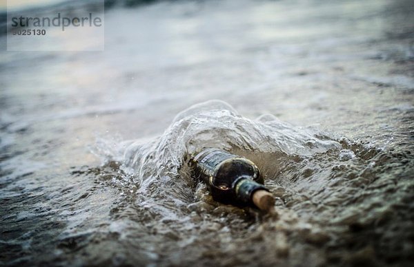 Flaschenpost - Flasche halb im Sandstrand vergraben