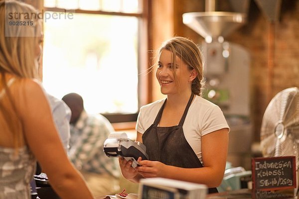 Junge Frau serviert Kunden im Coffee-Shop