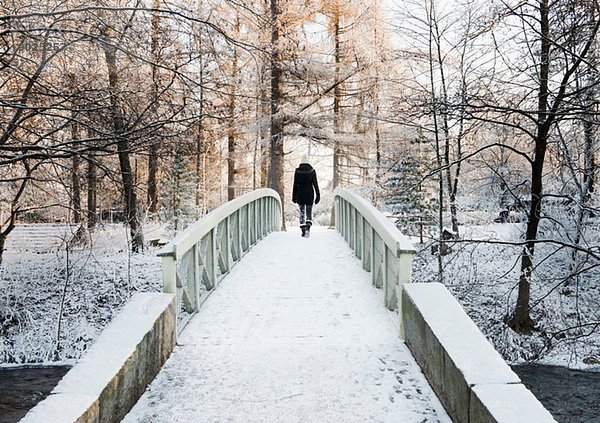 Frau überquert schneebedeckte Brücke  Rückansicht