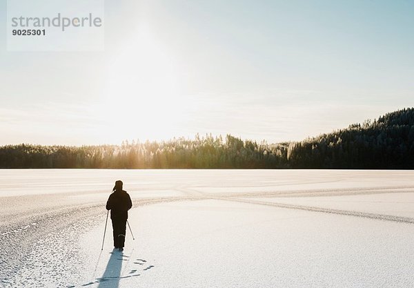 Erwachsener Mann Nordic Walking durch schneebedecktes Feld