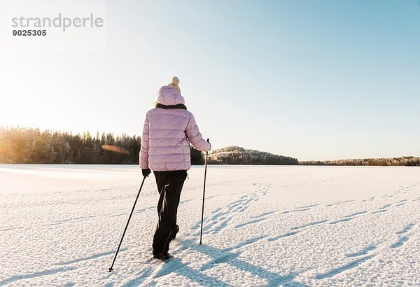 Frau Nordic Walking durch schneebedecktes Feld